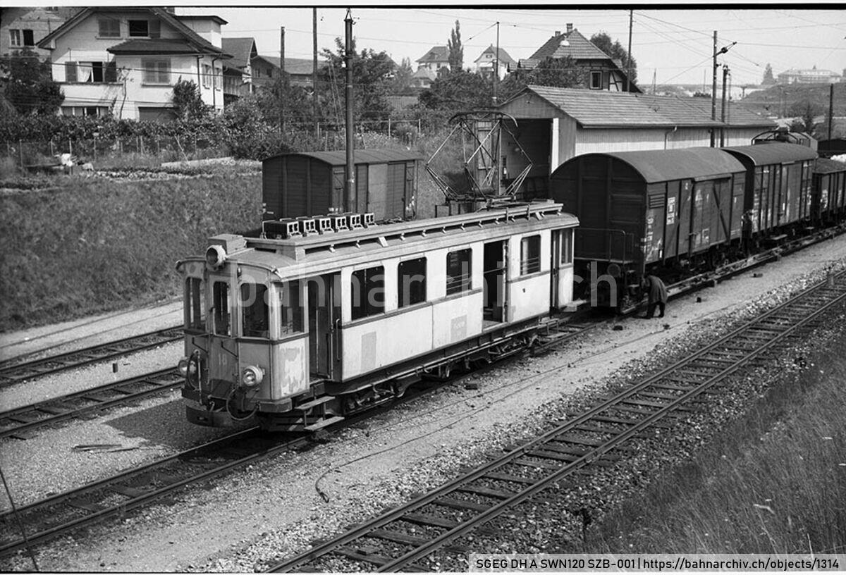 SGEG DH A SWN120 SZB-001: Triebwagen Fe 4/4 18 der Solothurn-Zollikofen-Bern-Bahn (SZB) mit Güterwagen auf Rollschemeln in Bolligen